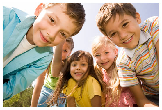 5 special education children smiling happily at you in outdoors sunshine